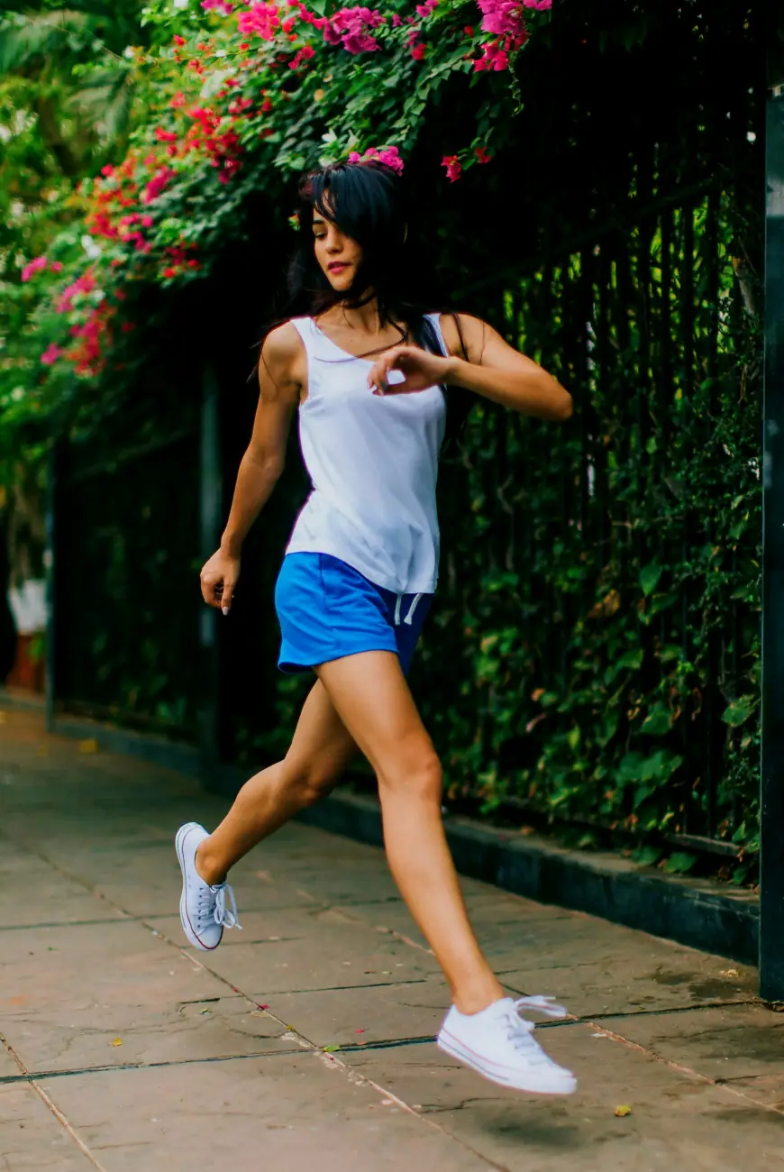 Mujer corriendo junto a flores y vegetación, representando como escucha y conecta con su cuerpo.